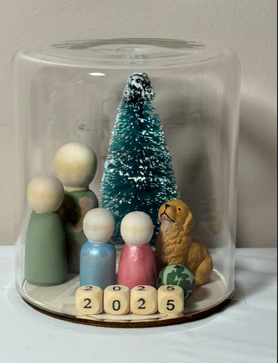 Personalized family memorial globe with handmade figures, a dog, tree, and the year 2025